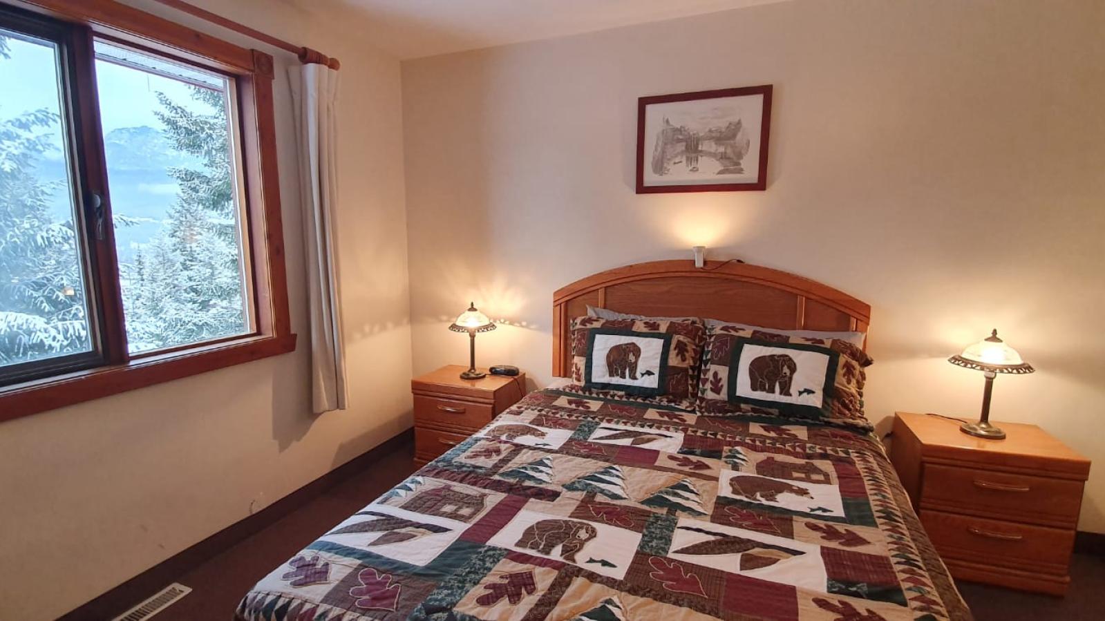 A bedroom with pine bedstead with cozy Canadiana quilts and pine nightstands