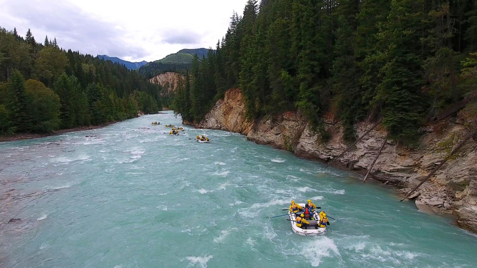 Whitewater rafters in a white raft enjoy the calm Kicking Horse River.